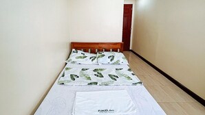 A small, neatly made bed with a white mattress and green leaf-patterned bedding. - Flogel Amore Pension House (Cebu City)