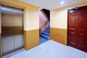 A hallway with a closed elevator, a staircase with a black railing, and a door marked with the number 401. - Flogel Amore Pension House (Cebu City)