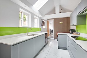 Una cocina moderna con una isla central, lavadora incorporada y un amplio ventanal que proporciona luz natural.