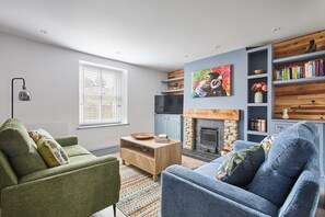 Una sala de estar moderna con chimenea, estantería y televisor.