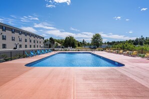 Una piscina al aire libre de temporada, sombrillas