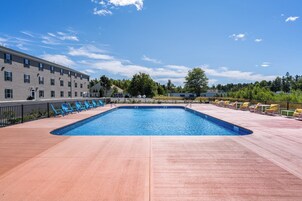 Una piscina al aire libre de temporada, sombrillas