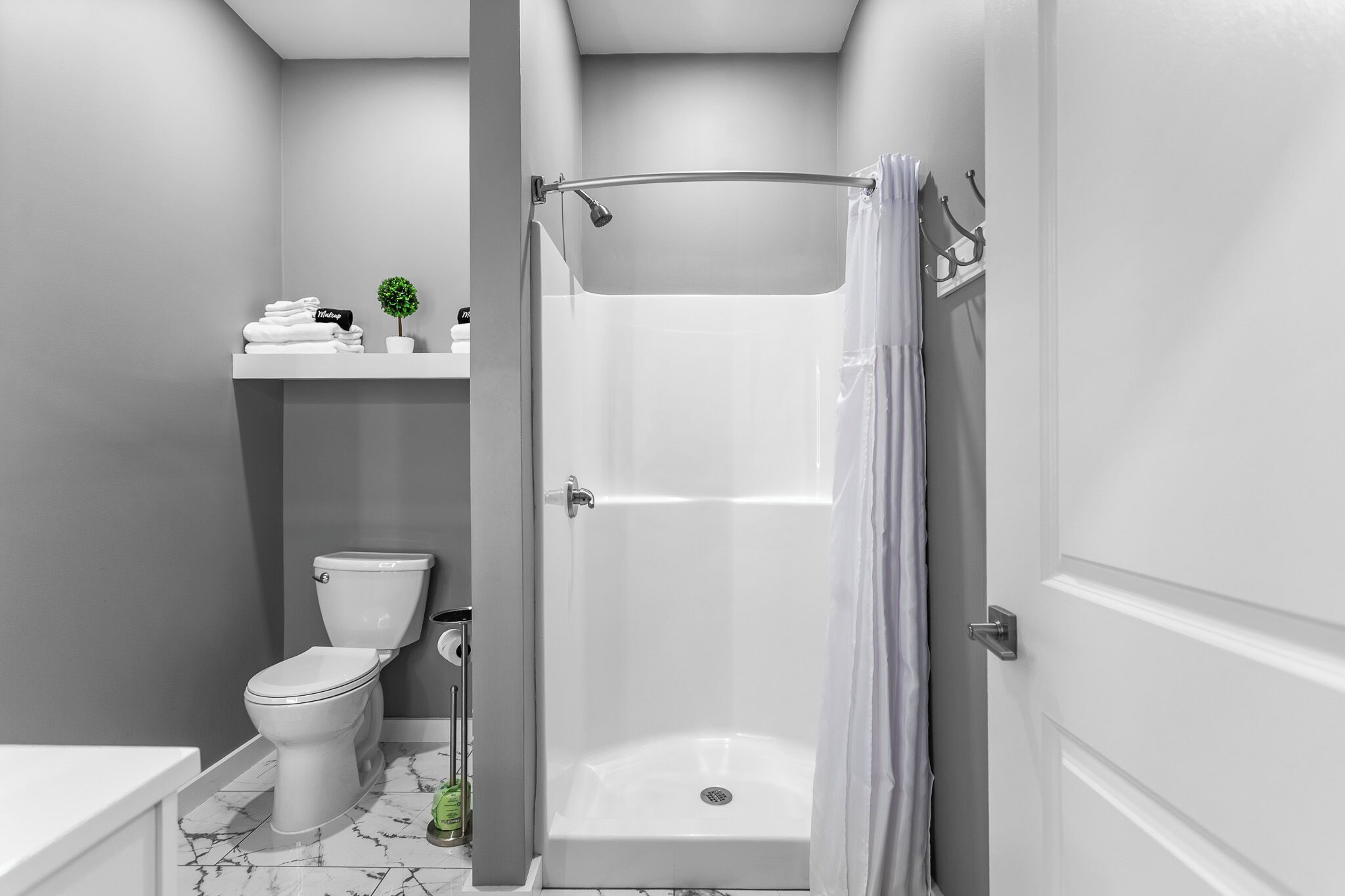 A bathroom with a toilet, a shower, and a sink.