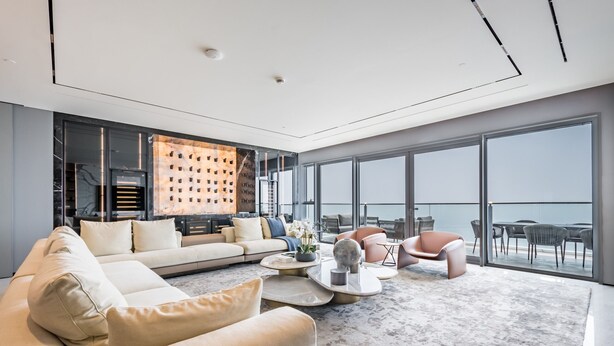 Un salon moderne avec un grand canapé, une table basse et un coin repas avec des chaises.