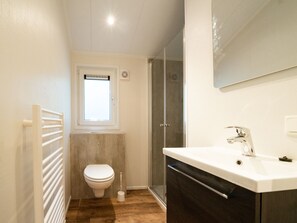 A compact bathroom with a toilet, a shower, and a sink.