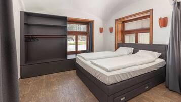 Ein Schlafzimmer mit einem Bett, Einbauschränken und zwei Fenstern mit Jalousien.