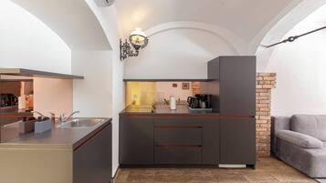 A compact kitchen with a modern design, featuring a built-in sink, a coffee machine, and a brick accent wall.