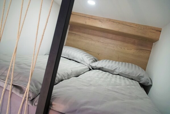 Un lit avec une tête de lit en bois et une literie grise.