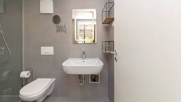 Un baño moderno con inodoro, lavamanos y ducha.