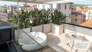 Un balcon avec un jacuzzi, des plantes en pot et une vue sur la ville.