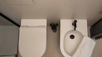 Een badkamer met een toilet en wastafel, beide wit, en een handdoek aan de wastafel.