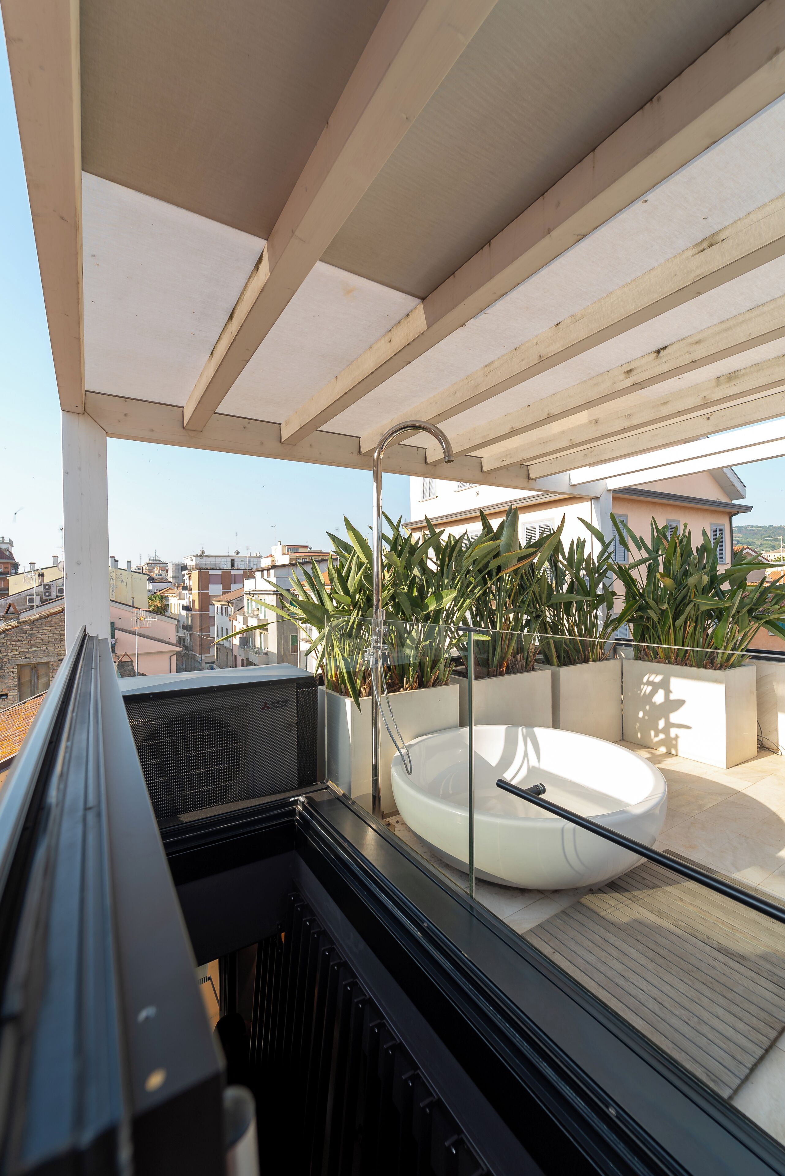 Un balcón con bañera integrada, plantas en macetas y vista a la ciudad.