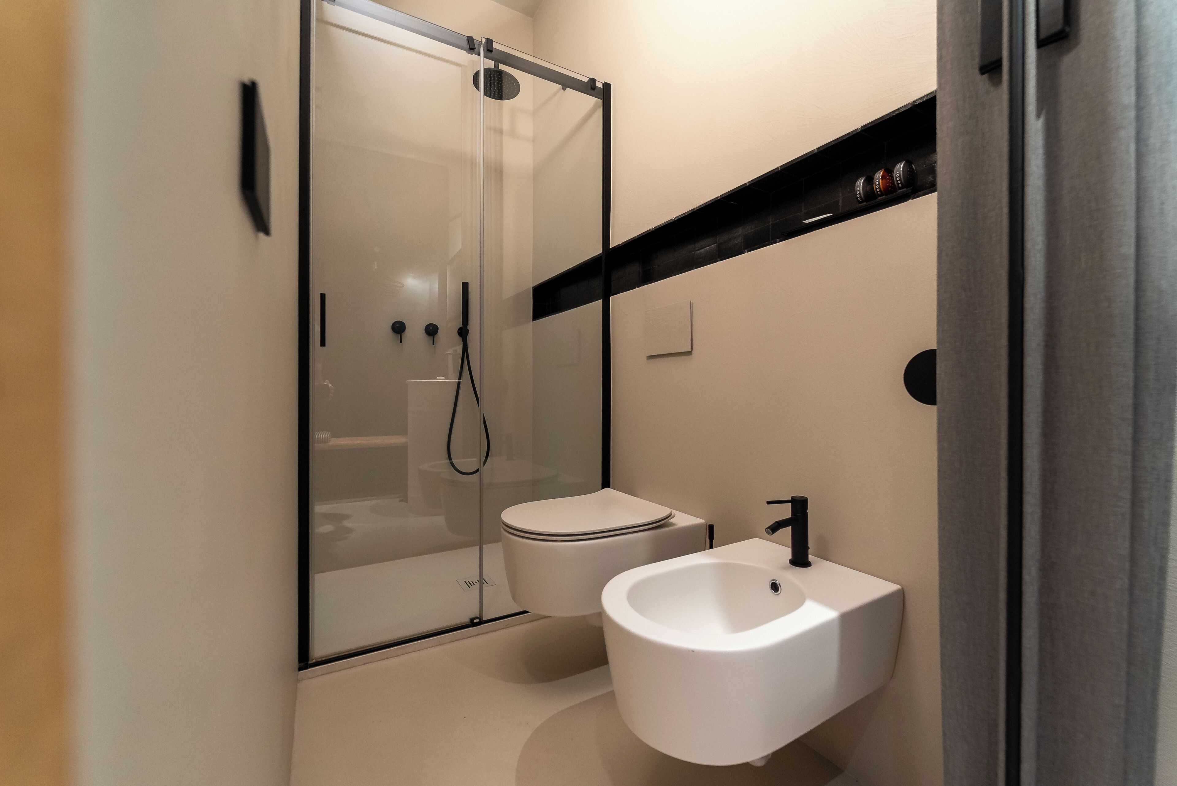 Un baño moderno con ducha envuelta en vidrio, inodoro y lavamanos pedestal.