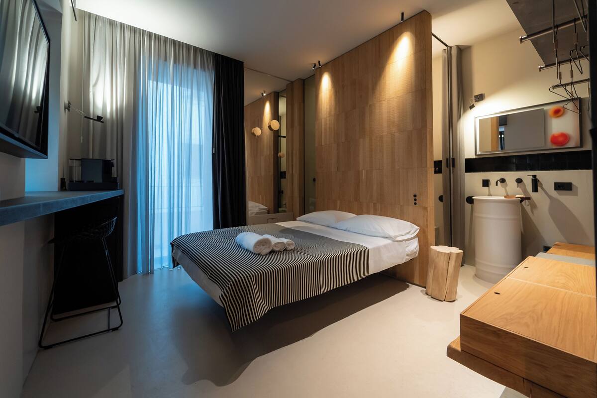 Una habitación de hotel moderna con una cama grande, una cómoda de madera, un espejo y un escritorio con una silla.