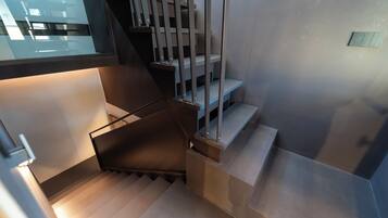 A modern staircase with metal railings and a glass window above.