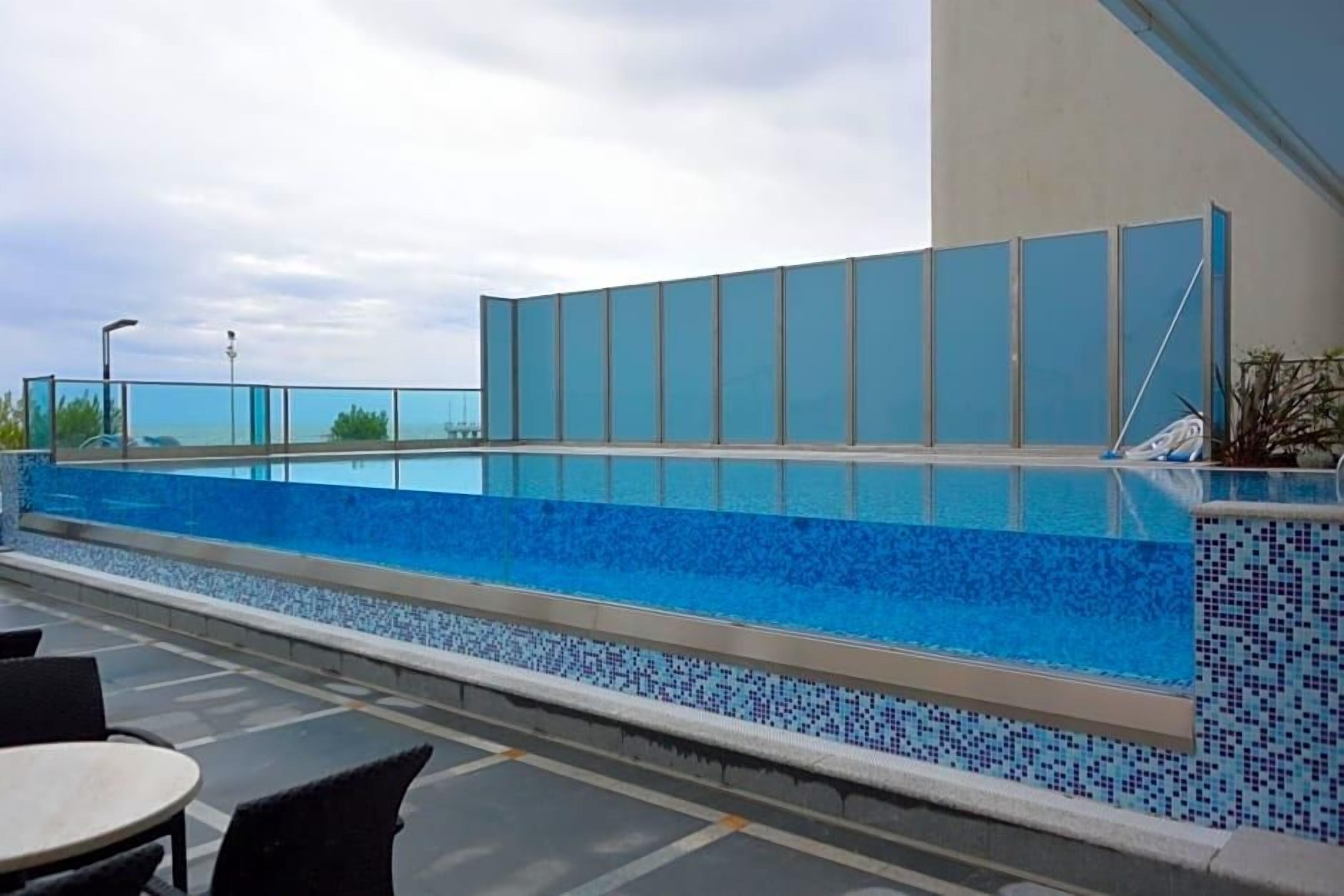Ein Dachpool mit klarem, blauem Wasser, umgeben von einer gefliesten Kante und einer Glasschutzwand.