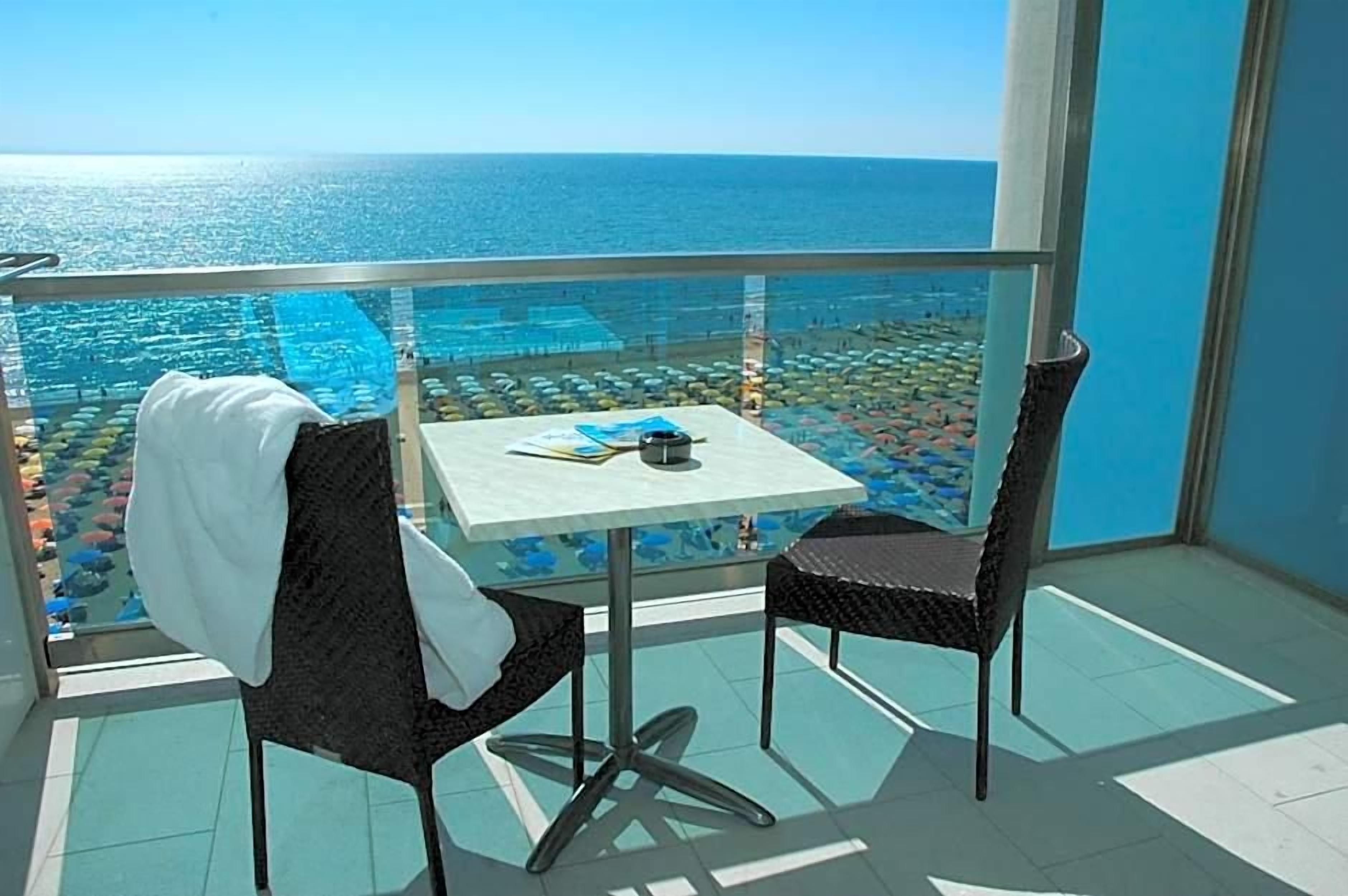 Ein Balkon mit Tisch und Stühlen mit Blick auf Pool und Strand.