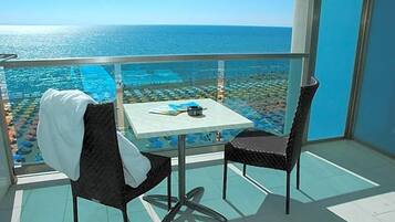 Ein Balkon mit Tisch und Stühlen mit Blick auf Pool und Strand.