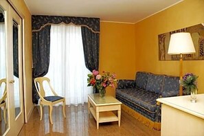 Una habitación con un sofá, una silla, una mesita con un florero y una lámpara.