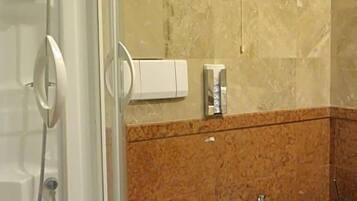 Een badkamer met douche, toilet, bidet en marmeren wanden.