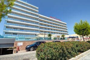 Ett hotell med flera våningar och modern design, med en tydlig skylt som visar texten ”HOTEL COLUMBUS”.