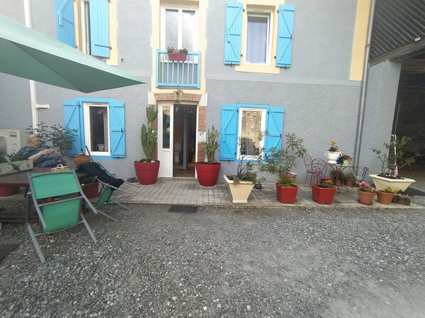Un patio con plantas en macetas, una mesa y sillas.