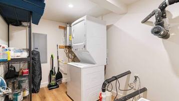 A laundry room with a white washing machine, a vacuum cleaner, and a water heater.