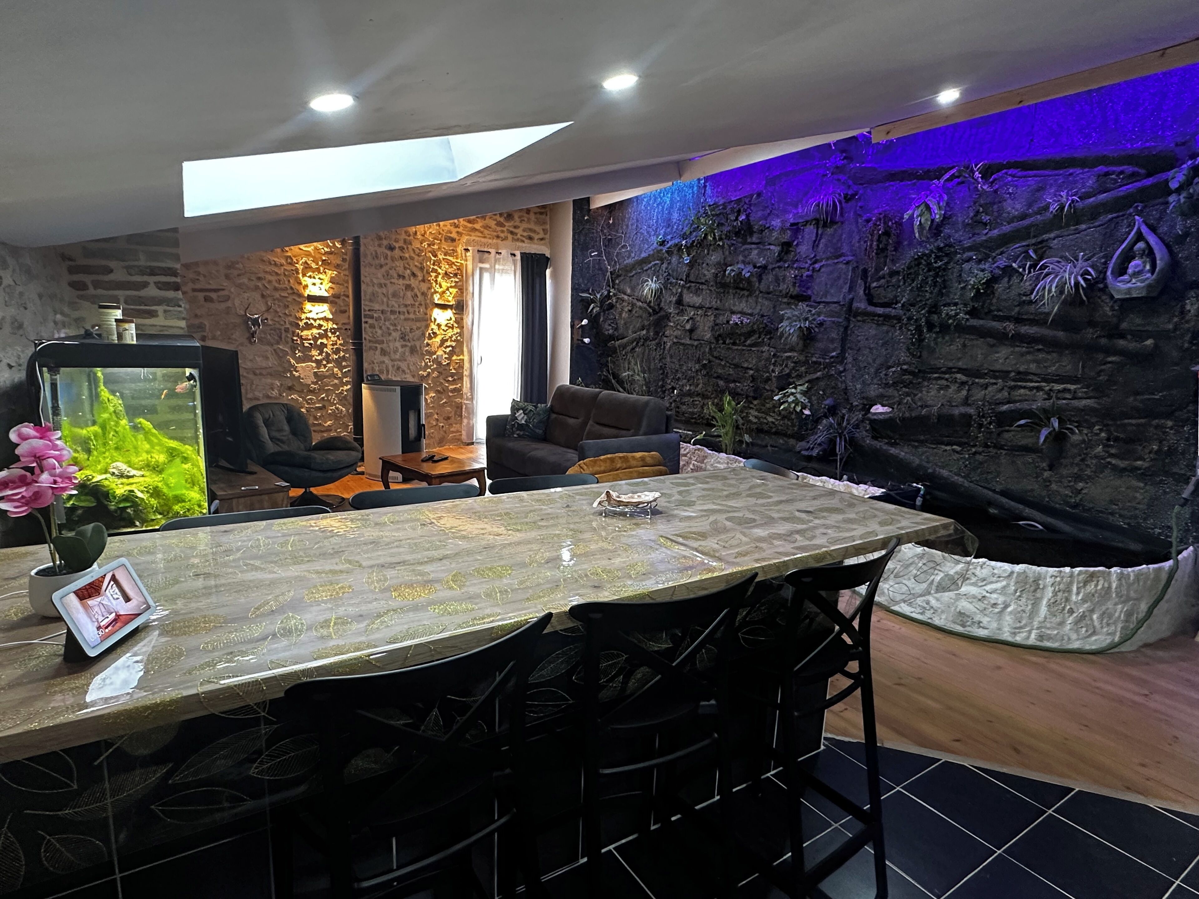 A modern living room with a stone wall, a large aquarium, and a seating area with a sofa and chairs.