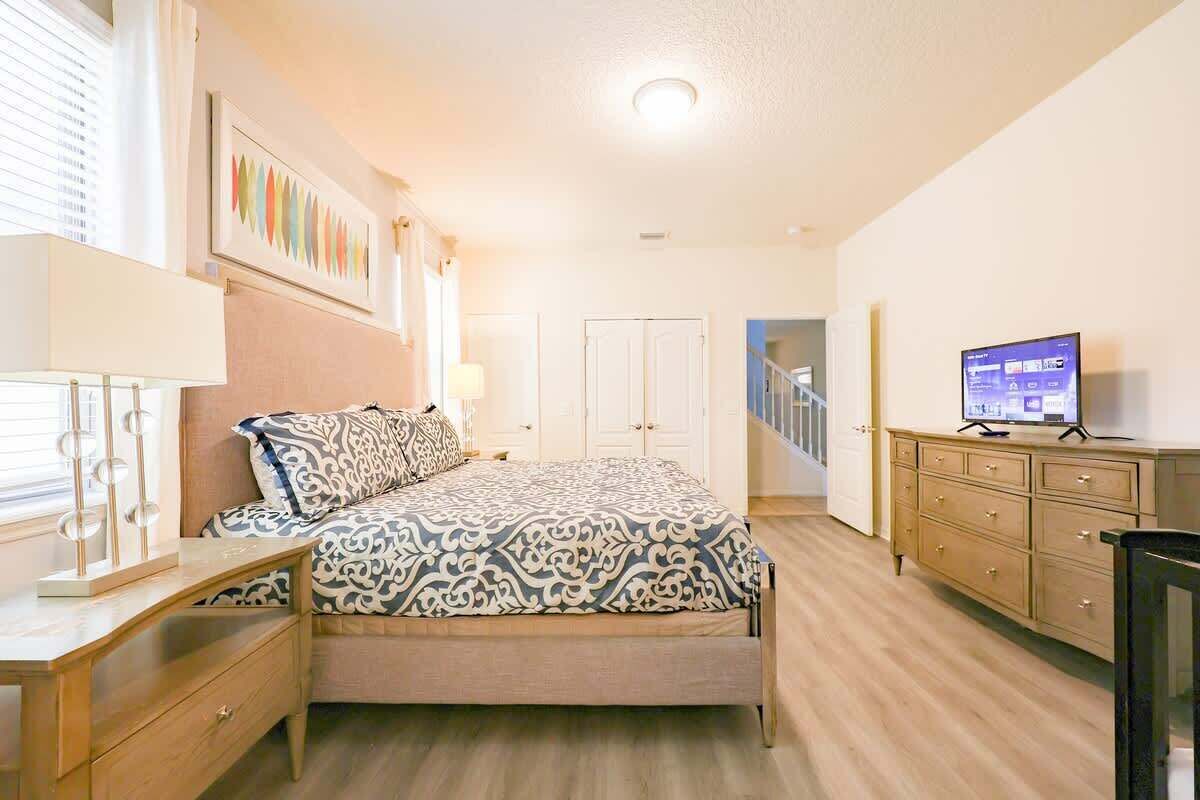 Een slaapkamer met een bed, een kaptafel, een televisie en een spiegel.