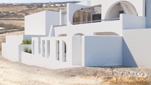 A modern white building with a flat roof, large windows, and a view of the surrounding landscape. - Mr & Mrs White Paros Suites & More (Paros)