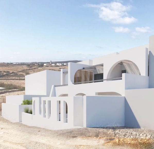A modern white building with a flat roof, large windows, and a view of the surrounding landscape.