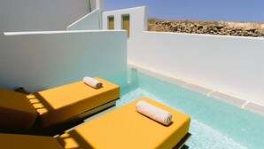 A pool area with two yellow sun loungers, one with a towel. - Mr & Mrs White Paros Suites & More (Paros)