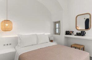 A minimalist bedroom with a bed, bedside table, lamp, and a small stool. - Mr & Mrs White Paros Suites & More (Paros)