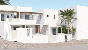 A modern white building with a balcony, a palm tree, and a person standing near the entrance. - Mr & Mrs White Paros Suites & More (Paros)