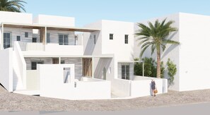 Un edificio moderno blanco con un balcón, una palmera y una persona de pie cerca de la entrada.