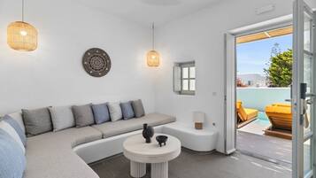 Una sala de estar moderna con un sofá modular, una mesa de centro redonda y una puerta de vidrio que da a una zona de estar exterior.