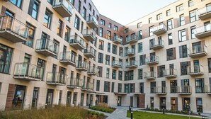 Ein modernes, mehrgeschossiges Wohngebäude mit Balkonen, einem zentralen Innenhof und einem angelegten Garten.