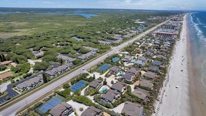 An aerial view of a coastal residential area with houses, a beach, and a road. - Luxury / Beachside / Pickle Ball / Surf / Pool (New Smyrna Beach)