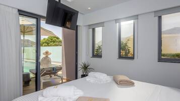 Een moderne hotelkamer met een groot bed, een aan de muur bevestigde televisie en een balkon met uitzicht op het landschap.