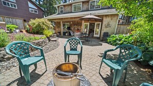 Un espace patio extérieur avec un pot en métal posé sur une table, entouré de chaises vertes.