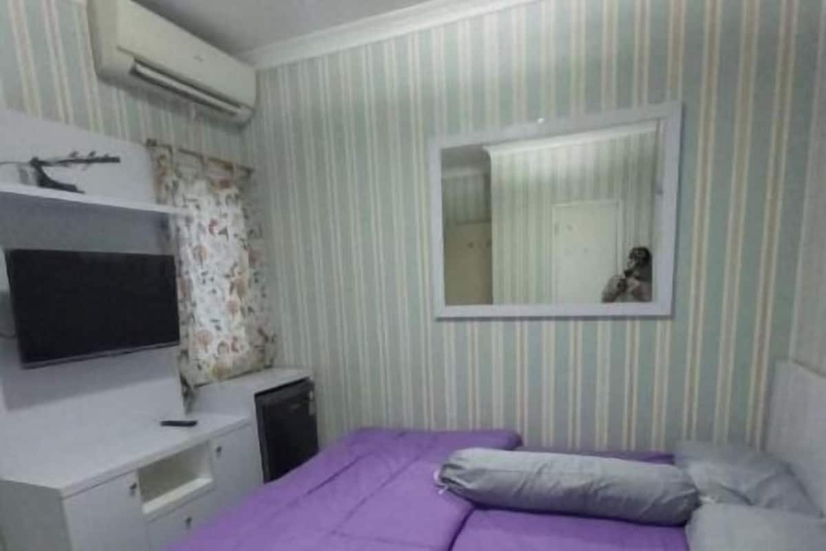 Ein Schlafzimmer mit Bett, Fernseher, Schreibtisch und Spiegel.
