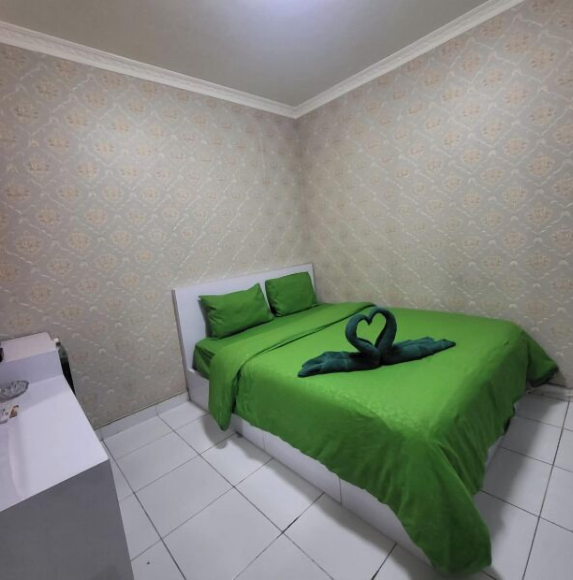 A small, neatly arranged bedroom with a bed, pillows, and a bedside table.