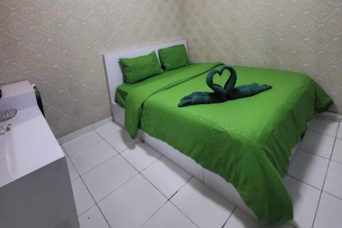 Ein kleines, ordentlich eingerichtetes Schlafzimmer mit einem Bett, Kissen und einem Nachttisch.