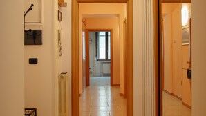 A hallway with a tiled floor, wooden doors, and a view into a room with a window. - - Holiday Home - Medieval Aqueduct - Salerno - (Salerno)