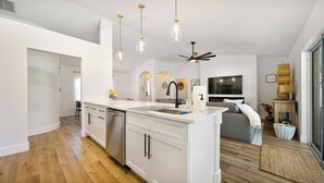 Una cocina moderna con armarios blancos, una isla central e iluminación colgante.