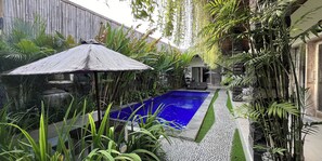 Una piscina rodeada de exuberante vegetación y una pérgola de madera.