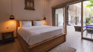 Un dormitorio con una cama de madera, dos lámparas de noche, un adorno en la pared y vistas a un área exterior con una mesa y sillas.