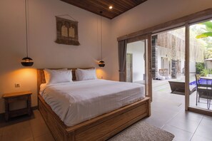 Un dormitorio con una cama de madera, dos lámparas de noche, un adorno en la pared y vistas a un área exterior con una mesa y sillas.