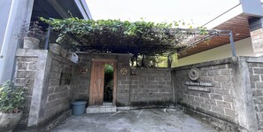 Una entrada de pared de piedra con una puerta de madera, una reja metálica y un letrero con un número de teléfono.
