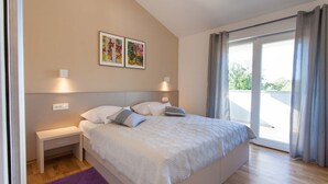 A modern bedroom with a large bed, bedside tables, a purple rug, and two wall-mounted artworks. - Villa Adrimar in Risika (Risika)